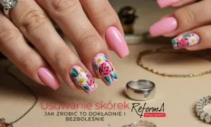 Dłoń z różowymi paznokciami ozdobionymi kwiatami. Delikatne kopytko i biżuteria dopełniają stylizację.
