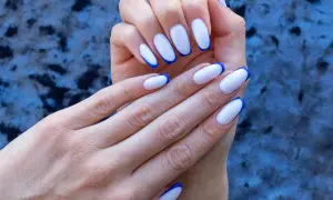 Dłonie z paznokciami w stylu niebieski french. Klasyczny manicure z odważnym, kobaltowym akcentem.