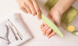 Dłonie z naturalnymi paznokciami, pilniczek, cążki i inne akcesoria do manicure. Dowiedz się, jak szybko zapuścić paznokcie.