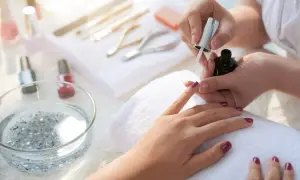 Aplikacja top coat na paznokcie. To ostatni etap manicure, który utrwala lakier i nadaje połysk.