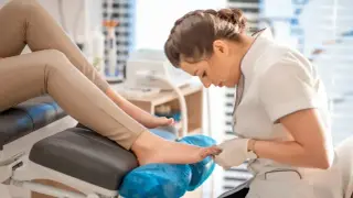 Profesjonalny pedicure co to? Stylistka dba o stopy klientki, wykonując zabieg pielęgnacyjny.