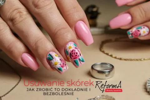 Dłoń z różowymi paznokciami ozdobionymi kwiatami. Delikatne kopytko i biżuteria dopełniają stylizację.