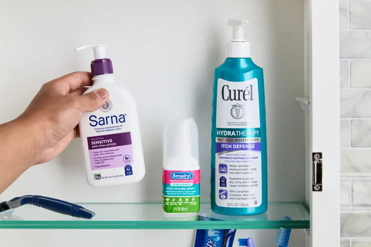 Dłonie sięgają po Sarna Sensitive Anti-Itch Lotion, obok sprayu Benadryl i kremu Curél. Produkty te pomagają złagodzić suchą, swędzącą skórę.