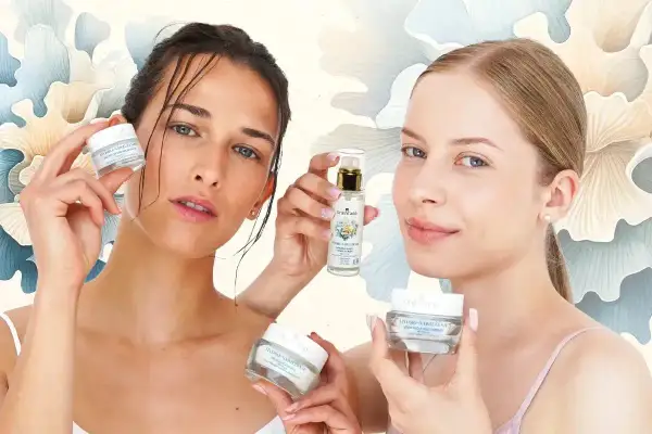 Dwie kobiety prezentują kosmetyki. Jedna trzyma krem, druga serum. Produkty pomagają regulować sebum i nawilżać skórę.
