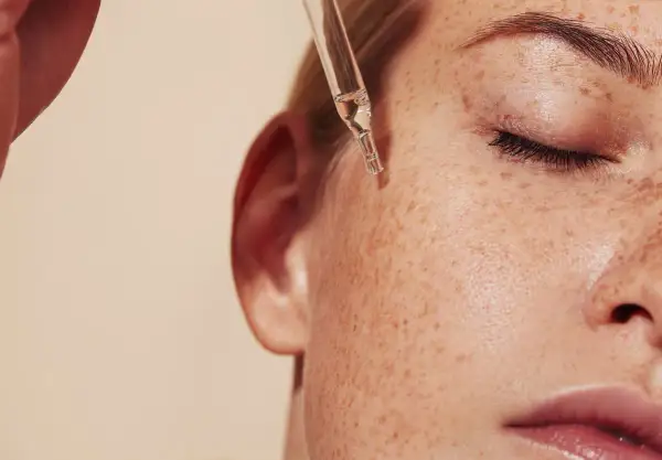 Kropla serum z pipety spada na piegowatą skórę. Czy to retinol? Co to jest retinol i jak działa na skórę?